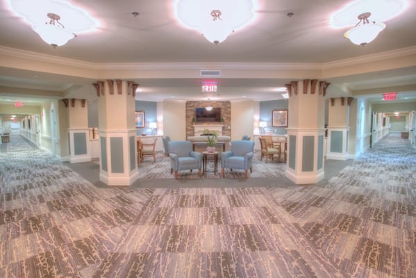 A spacious hallway in Tapestry House Assisted Living, featuring comfortable seating and decorative lighting.