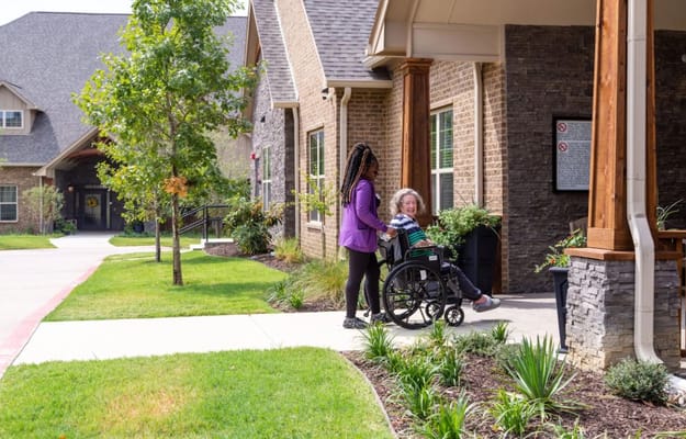 A staff member assists a resident in a wheelchair at the entrance of Teresa's House.