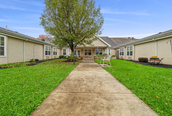 A pathway leading to the entrance of The Addison of Moorehead Place, surrounded by grass and trees.