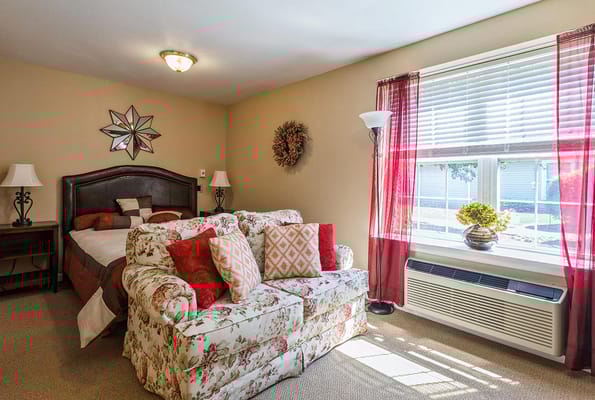A cozy bedroom with a floral couch and decorative pillows.