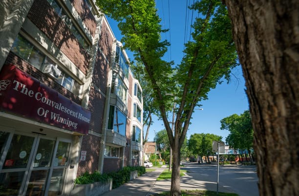 A building exterior with signage reading 'The Convalescent Home of Winnipeg' framed by trees.