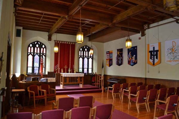 Interior view of the chapel with wooden beams and red banners
