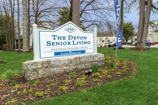 Sign for The Devon Senior Living facility located on green lawn