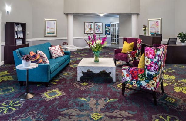 Colorful lobby seating area with floral chairs and a blue sofa.