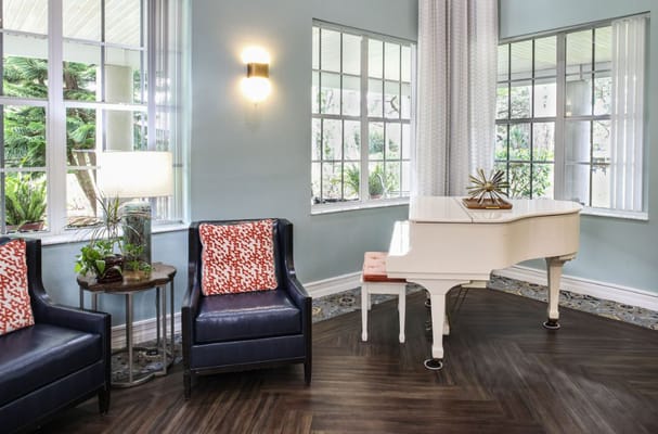 Cozy lounge area featuring a white piano and armchairs.