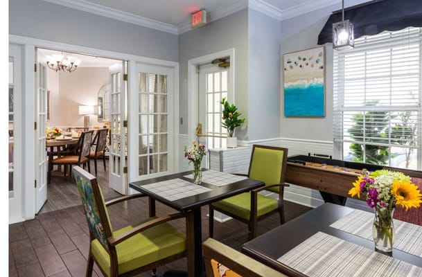 Cozy dining area with tables, flowers, and an art piece on the wall.