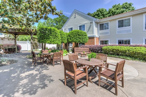 A tranquil outdoor seating area with wooden tables and chairs surrounded by greenery.
