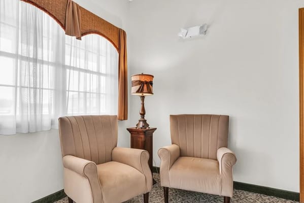 Two beige armchairs and a lamp by a window