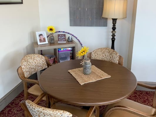 A round dining table with chairs, a vase of sunflowers, and a photo frame in a cozy setting.