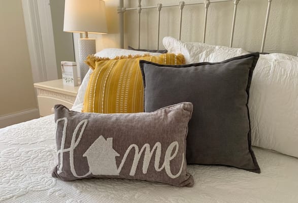 Pillows on a bed featuring a 'Home' decorative pillow