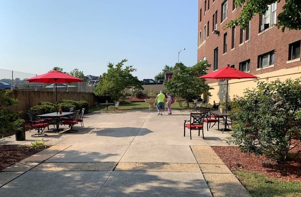 A sunny outdoor courtyard with red umbrellas and seating at The Kensington.
