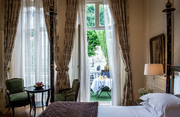 A cozy bedroom featuring a view of outdoor seating through large windows.