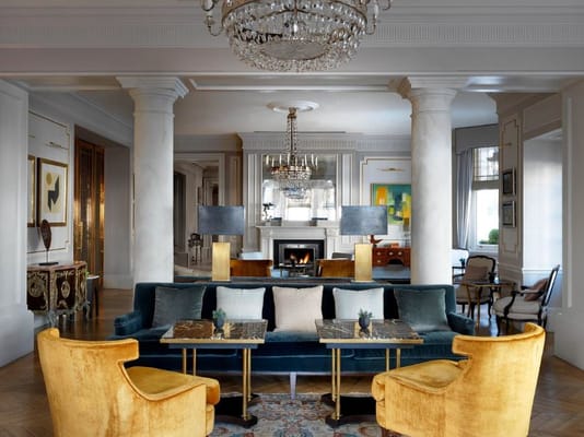 A beautifully designed lounge with a chandelier, sofas, and tables.