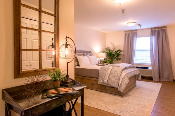 A beautifully arranged bedroom with a bed, nightstand, and decorative mirror.