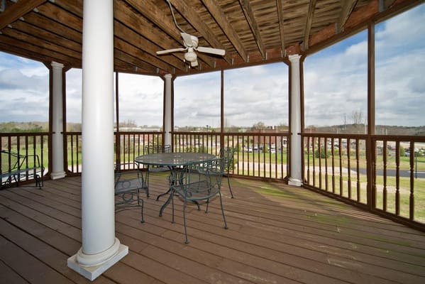 Covered porch with circular table and chairs surrounded by windows
