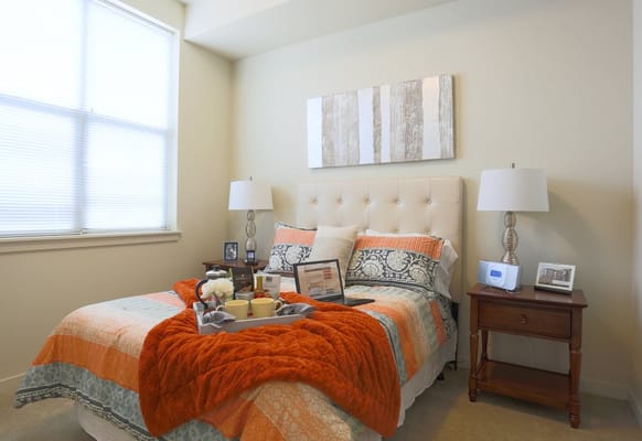 A well-decorated bedroom with an orange blanket and decorative pillows
