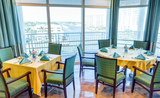 Spacious dining room with tables set for a meal and a view of the water