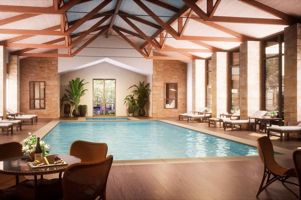 Indoor swimming pool with lounge chairs and large windows.