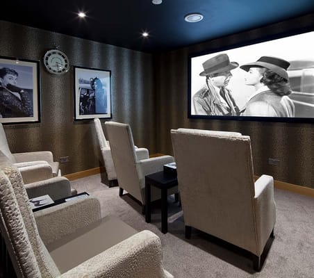 Comfortable chairs in a movie theater room with a classic film playing.