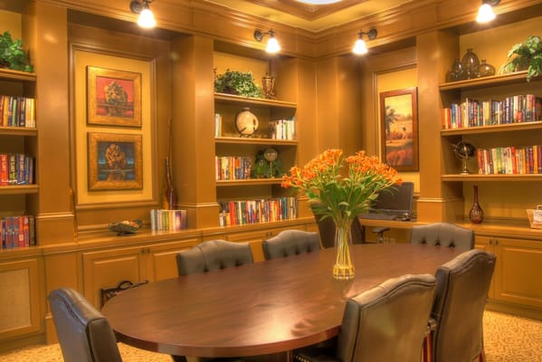 A cozy library meeting room with a large wooden table and bookshelves.