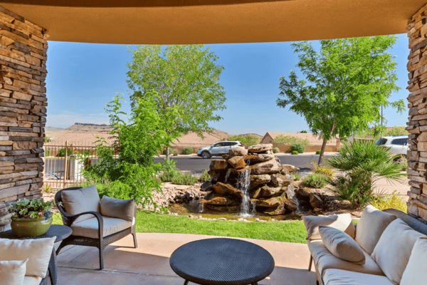 Outdoor seating area with a view of a rock waterfall and greenery