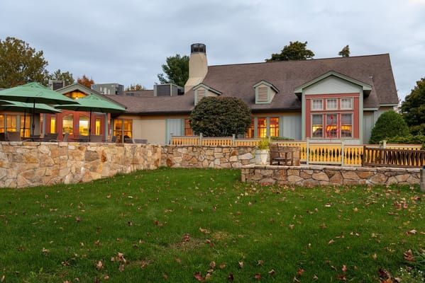 Exterior of The Scandinavian Living Center featuring a stone wall and green umbrellas.