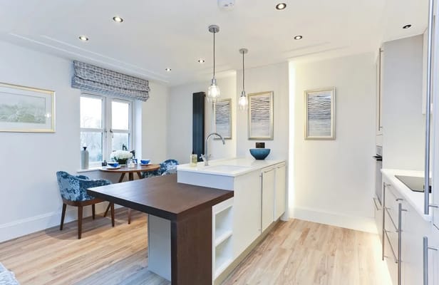 Contemporary kitchen and dining area featuring a table and chairs, with natural light from the windows.