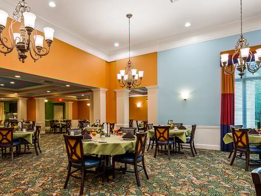 Brightly lit dining room with tables set for meals.