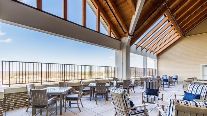 Seating area on the terrace with large windows and wood beams overhead.