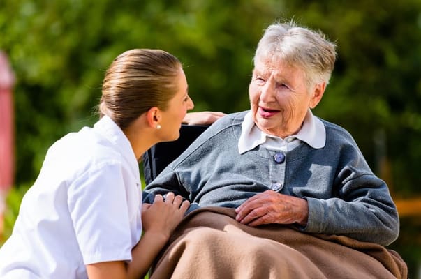 Caregiver speaking with a senior resident outdoors.