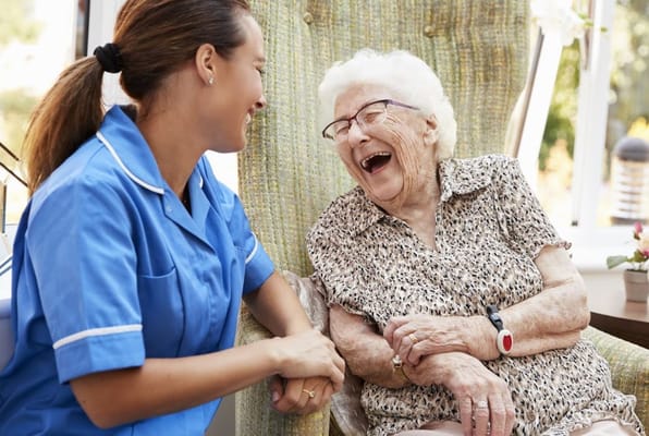 A caregiver and a senior resident sharing a laugh in a cozy setting.