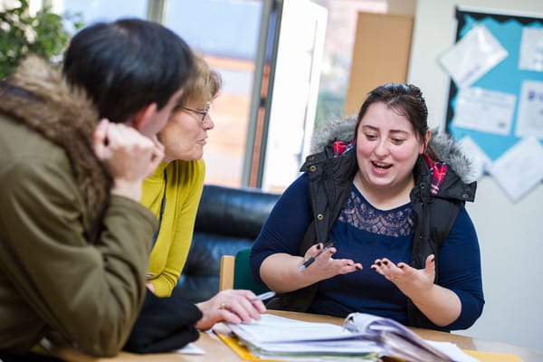 Three adults engaged in a lively discussion at a table with documents.