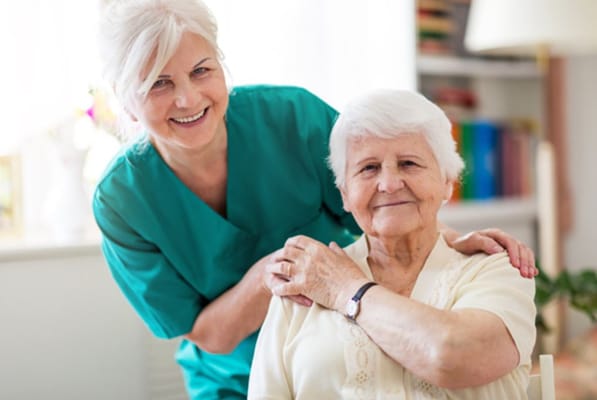 Caregiver smiling with a resident in a bright room