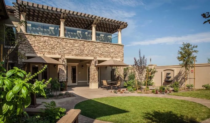 Stone-clad exterior with patio seating and landscaping at Villagio at Capriana