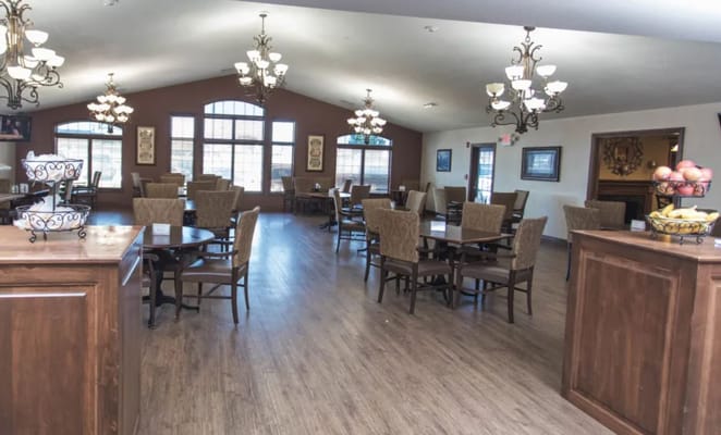 Brightly lit dining area with tables and chairs in Villas of Holly Brook Shelbyville.