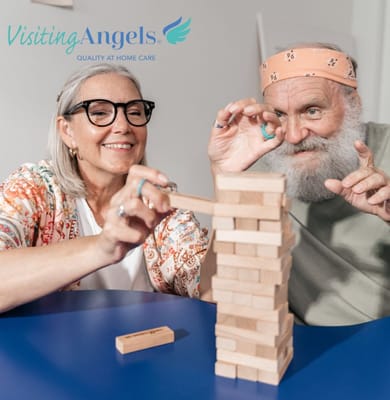 A woman and a man playing Jenga together at a table.