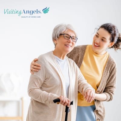 A caregiver assisting a senior woman with a cane, both smiling