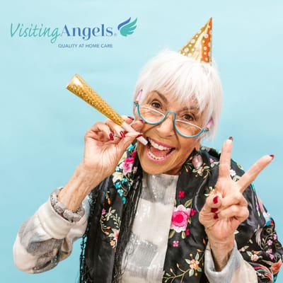 Elderly woman wearing a party hat, holding a noisemaker, and smiling