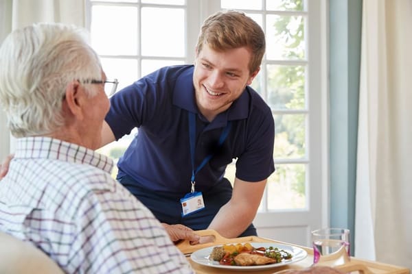 Caregiver serving a meal to a senior resident