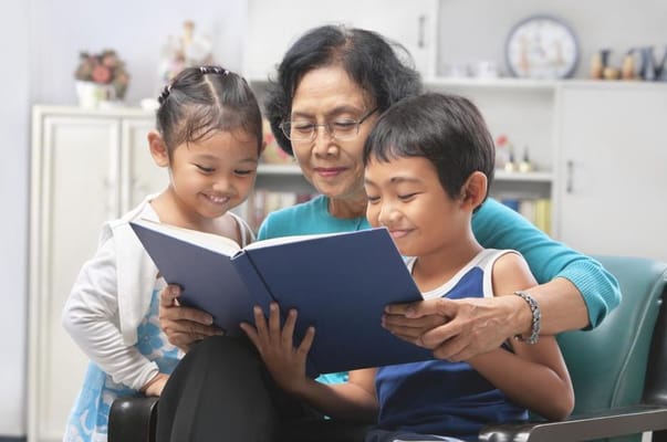 An elderly woman reading with two children