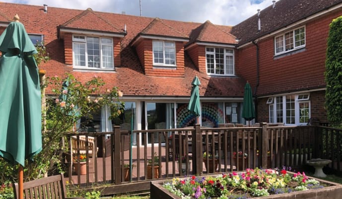 Exterior view of a care home with a garden and seating area