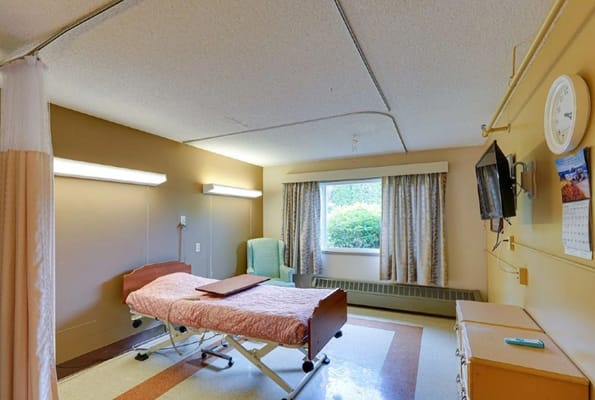 Private resident room with a hospital bed and chair