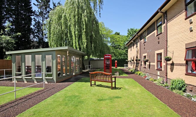 Outdoor garden space with a bench and nearby phone booth