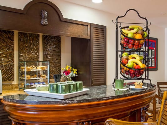 A display of fresh fruits and pastries at a senior living facility kitchen.