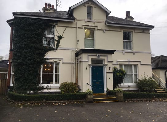 Front exterior of Woodlands Care Centre featuring a blue door and ivy-covered wall.