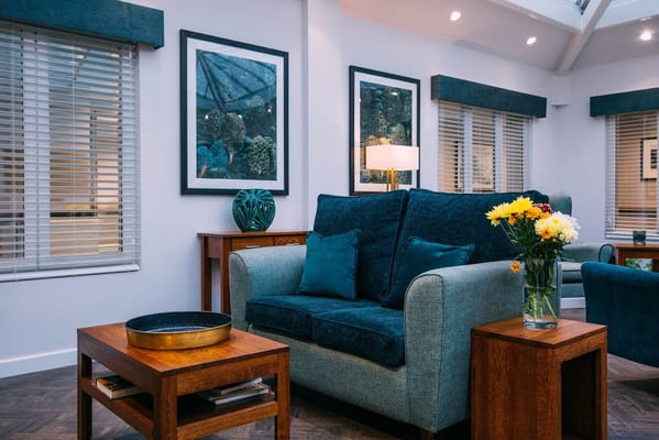 Living room with a blue sofa, wooden tables, and decorative plants.