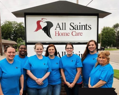 Staff members posing in front of the facility sign