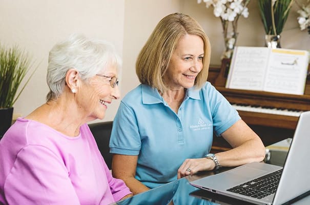 Resident and staff member sharing a moment over a laptop