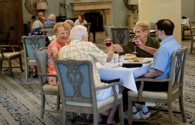 Residents enjoying a meal and toasting in the dining room