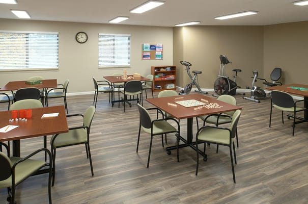 Bright interior common area with gaming tables and exercise equipment